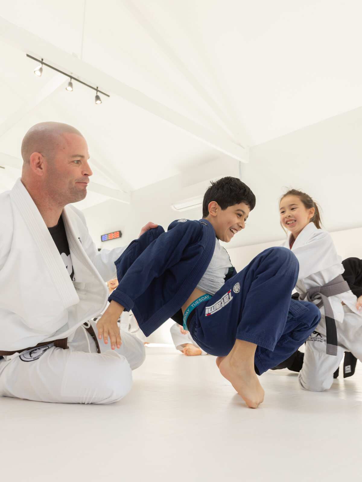 John-Henry Mallam coaching two laughing students in the kids class at Inner Westside BJJ